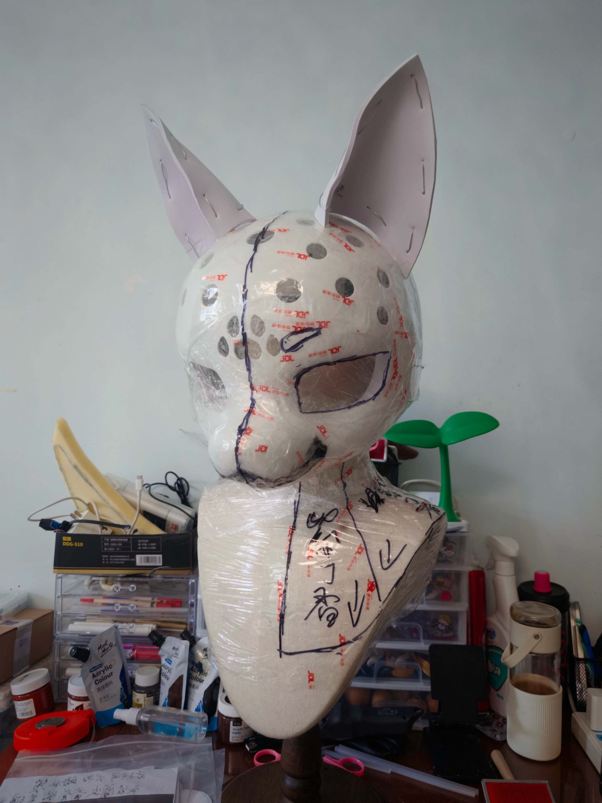 Behind the scenes fursuit head base in progress, foam and tape construction with pattern markings in artist's workshop